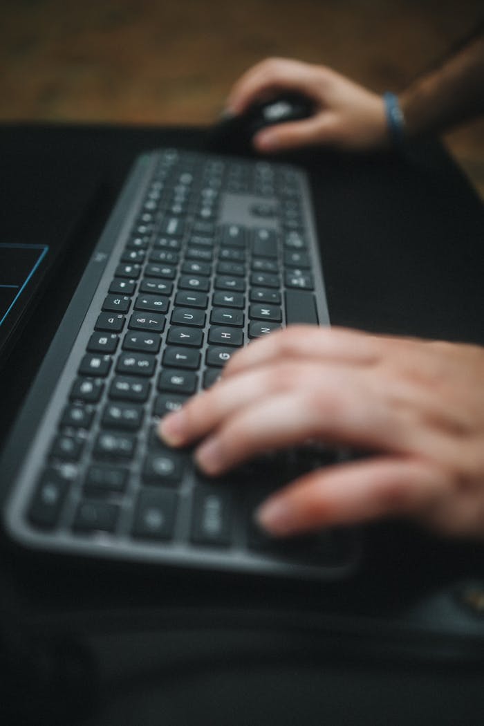 Hands typing on a keyboard with a focus on the movement and technology use.