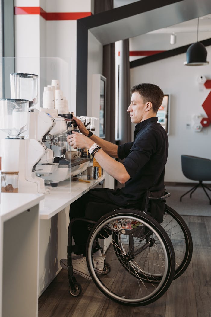 services-03 Barista in a wheelchair making coffee at a modern café, showcasing accessibility.