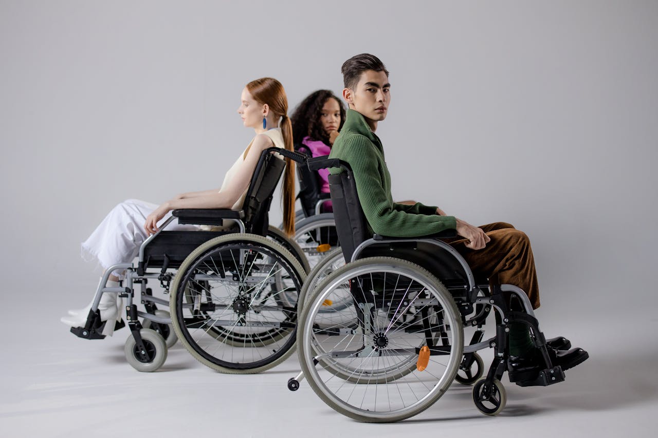 Three diverse individuals in wheelchairs posing indoors, symbolizing inclusivity.